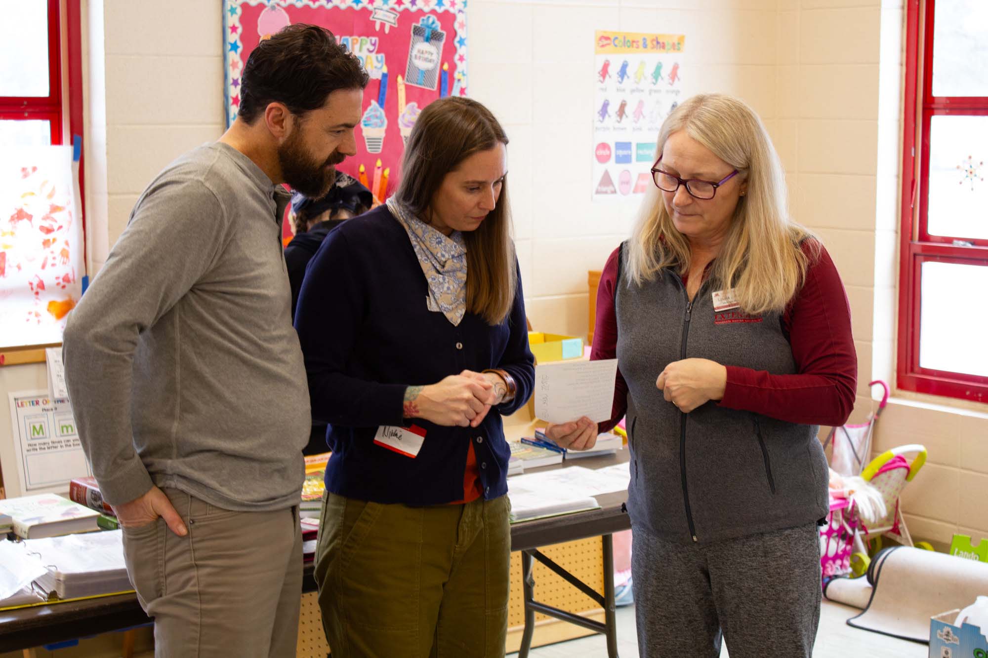 three standing people examining a piece of paper