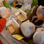 hands, milk jugs, dirt and seed packets on a table