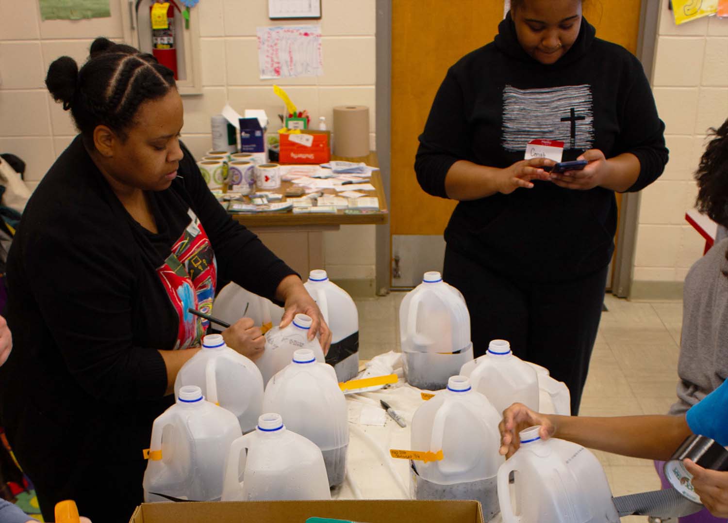 People working on filling and labelling milk jugs with native plant seeds