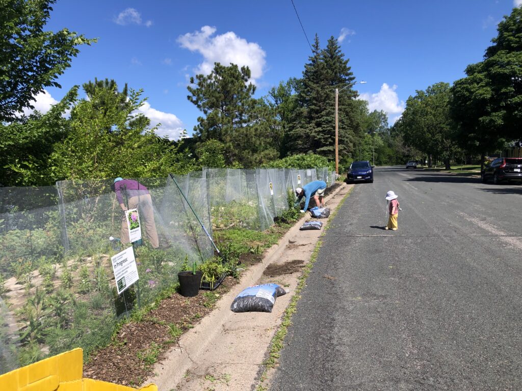 Two adults and a child working in a roadside garden