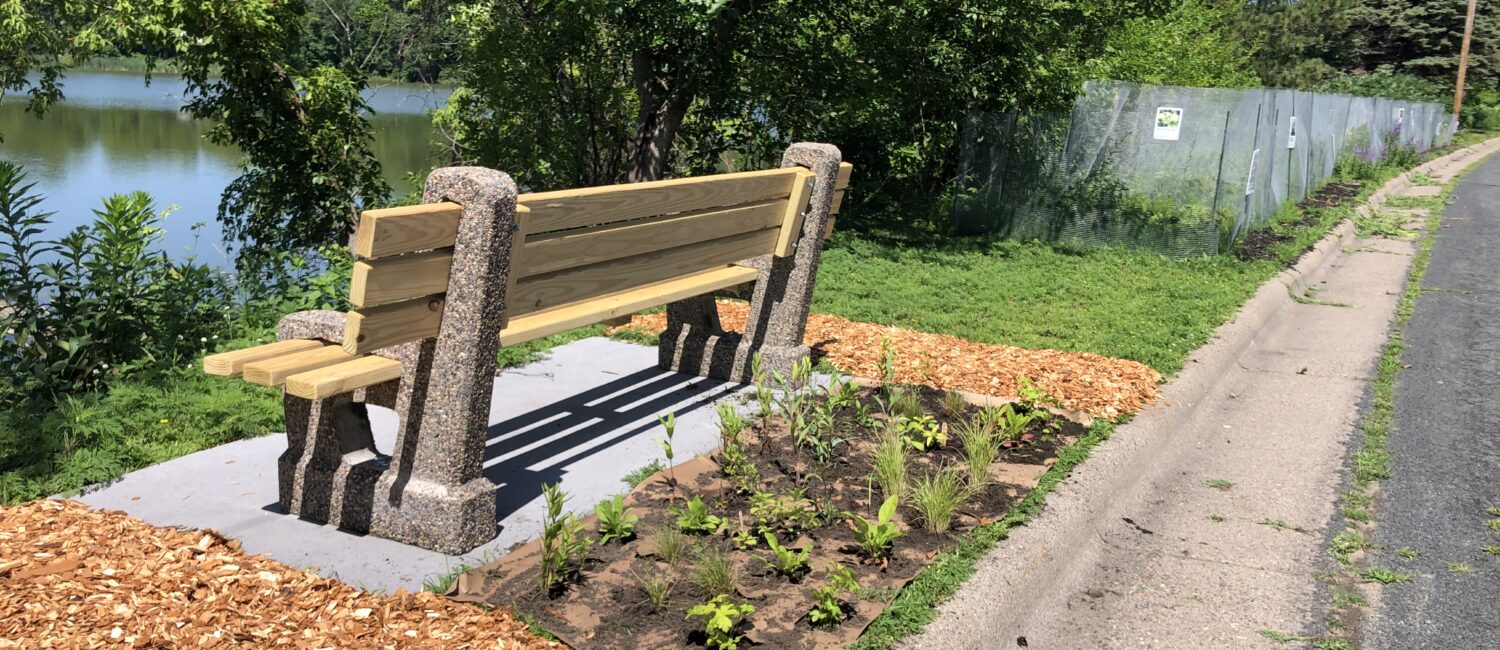 a wood and cement bench with cedar chips and fresh plantings