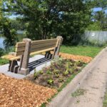 a wood and cement bench with cedar chips and fresh plantings