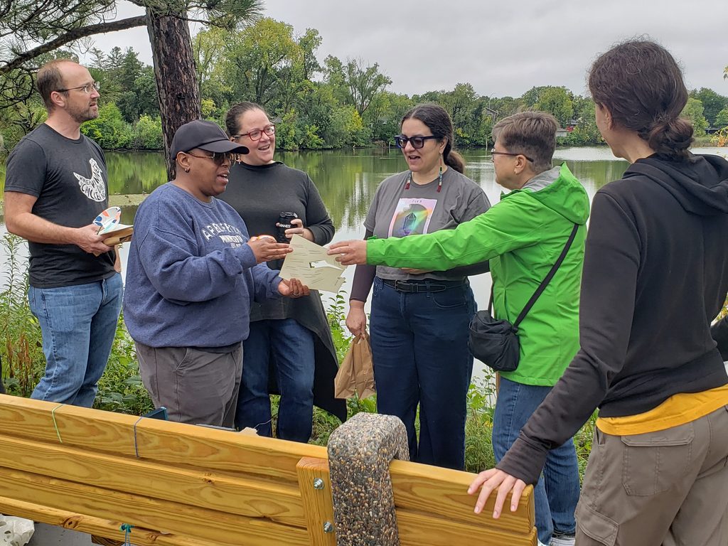 Group of people talking about ink on paper at the edge of Grass Lake Wetland